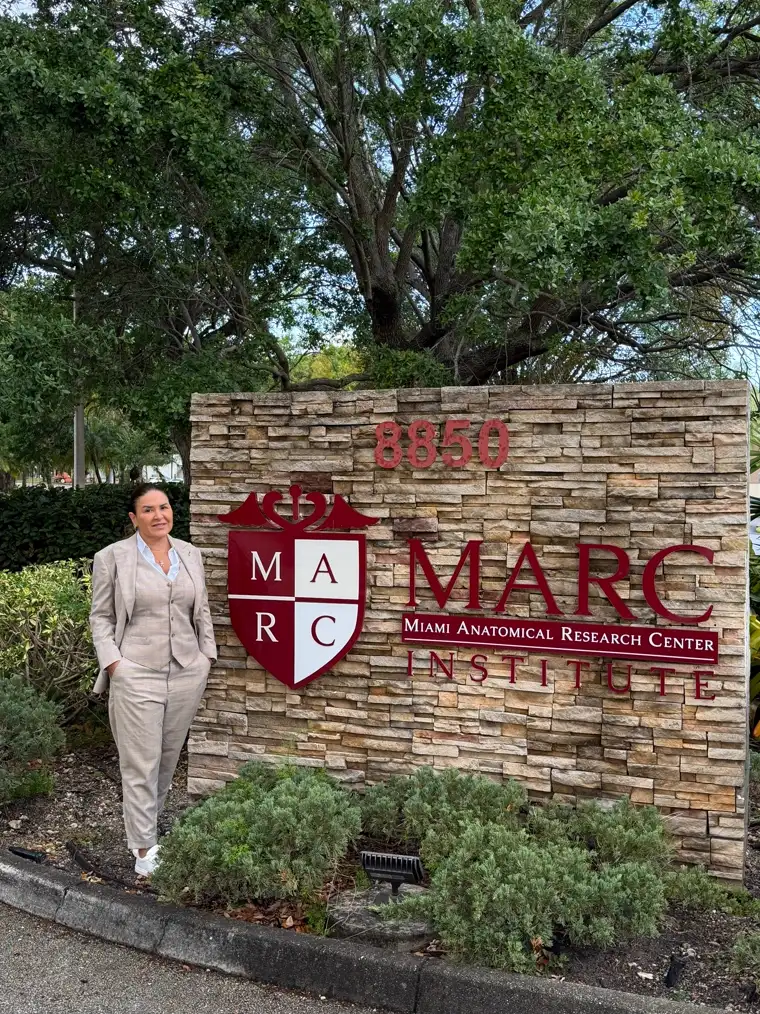 Dra. Camila Sandoval no letreiro do MARC Institute, o Miami Anatomical Research Center